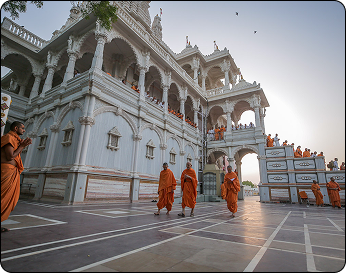 Monks in saffron robes walking at sacred temple in Braj